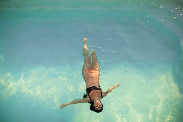 Aerial view of swimming woman floating in swimming pool