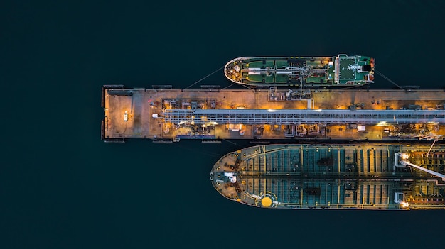 Aerial view tanker ship vessel unloading at port at night Global business logistic import export oil and gas petrochemical with tanker ship transportation oil from dock refinery