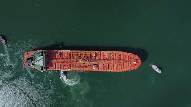 Aerial view of tanker ship with escorting tug leaving port