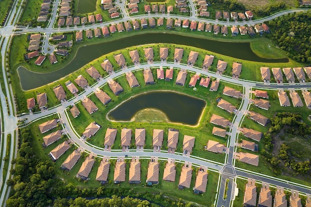 Aerial view of tightly located family houses with retention ponds to prevent flooding in Florida closed suburban area Real estate development in american suburbs