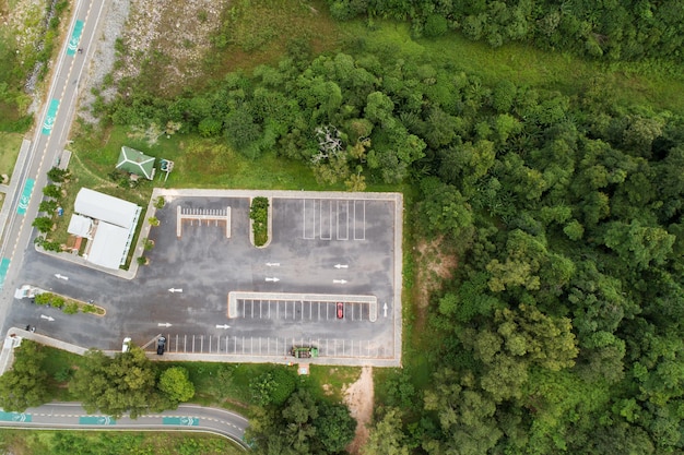 Aerial view top down of red SUV car parked at concrete car parking lot with white line of traffic sign on the street Above view of car in a row at parking space Outside car parking area