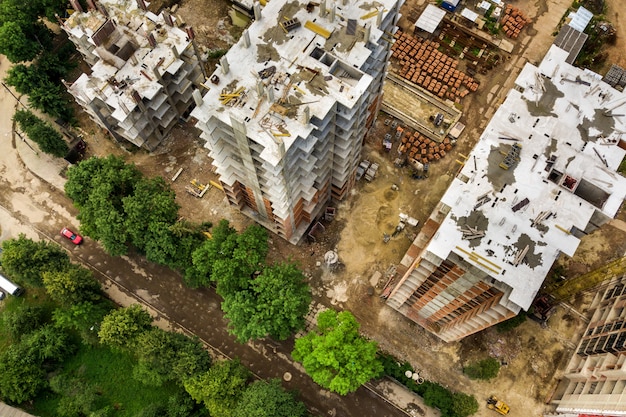 Aerial view of tower lifting crane and concrete frame of tall apartment residential buildings under construction in a city.