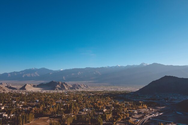 Aerial view of townscape by mountains against clear blue sky