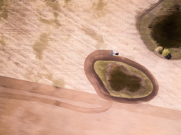 Aerial view of the tractor in the field, agricultural field work. Tractor cultivating field, aerial view