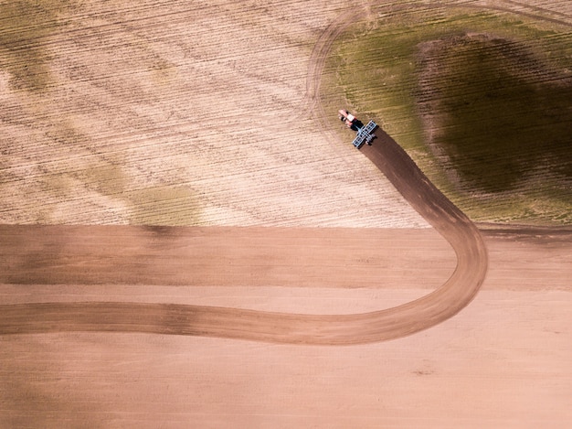 Vista aerea del trattore nel campo, lavoro agricolo del campo. trattore che coltiva campo, vista aerea