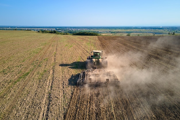 Aerial view of tractor plowing agriculural farm field preparing soil for seeding in summer