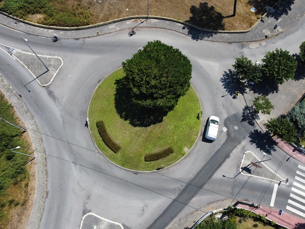 Aerial view of a tree in a traffic circle with a car on the road