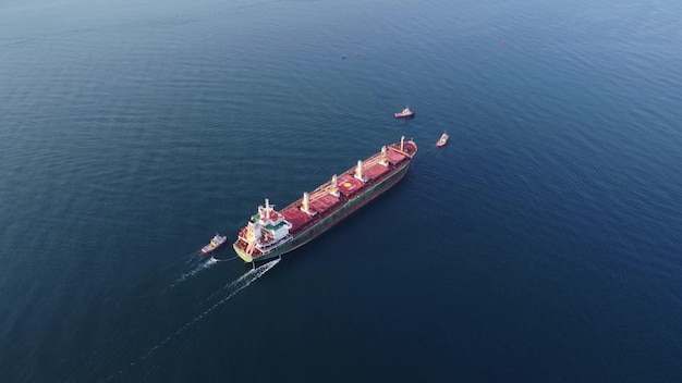 Aerial view of tug boat assisting big bulk carrier cargo ship\
large ship escorted by tugboat