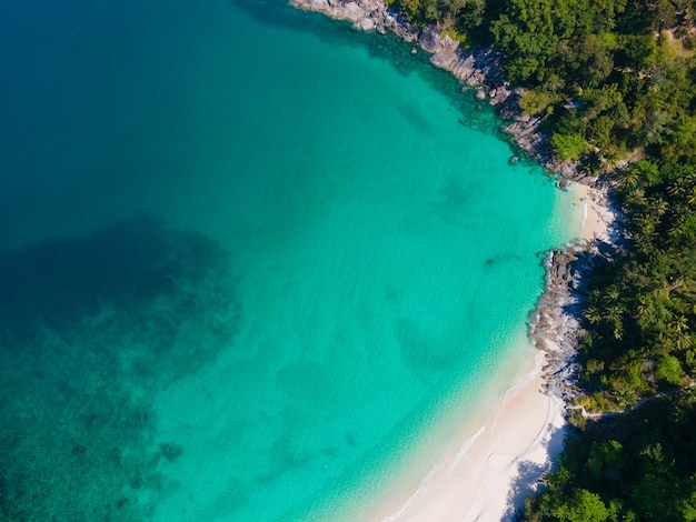 Aerial view of turquoise beach with white sand and jungle
