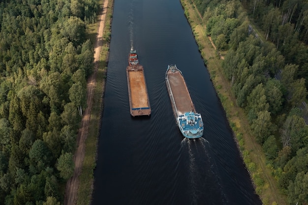 Aerial view of two barges diverging along a narrow channel in opposite directions