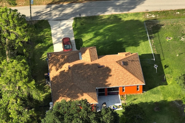 Aerial view of typical contemporary american private house with roof top covered with asphalt shingles and green lawn on yard