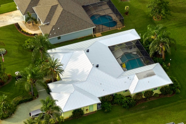 마당에 아스팔트 슁글과 푸른 잔디로 덮인 지붕이 있는 전형적인 현대 미국 개인 주택의 공중 전망