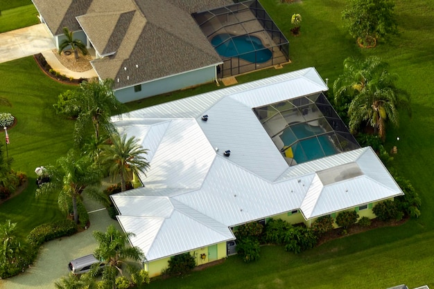 Aerial view of typical contemporary american private house with roof top covered with asphalt shingles and green lawn on yard