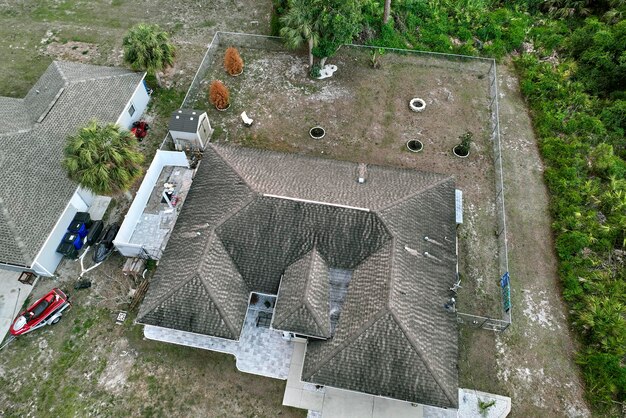 Aerial view of typical contemporary american private house with roof top covered with asphalt shingles and green lawn on yard