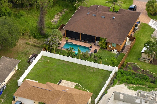 Aerial view of typical contemporary american private house with roof top covered with asphalt shingles and green lawn on yard