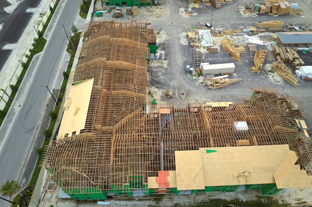 Aerial view of unfinished frames of apartment buildings ready for mounting wooden roof beams under construction Development of residential housing in american suburbs Real estate market in the USA