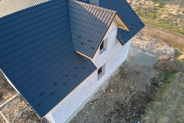 Vista aerea della casa incompiuta con pareti in calcestruzzo leggero aerato e struttura del tetto in legno ricoperta di piastrelle metalliche in costruzione.