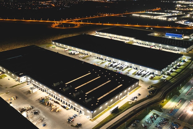 Aerial view of a warehouse of goods at night Aerial view of industrial area logistics warehouses and many trucks at night