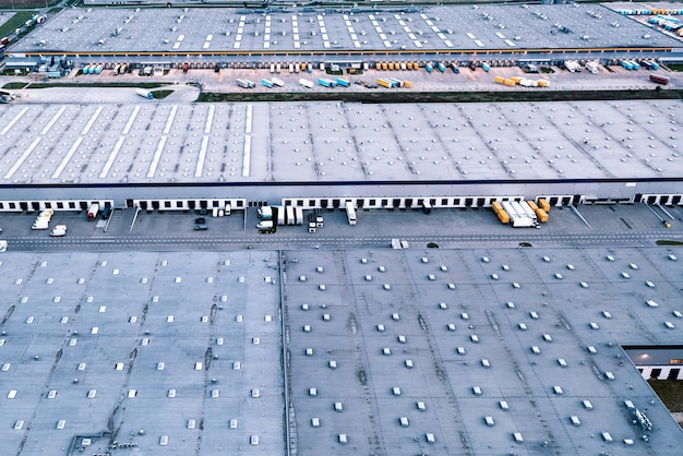 Aerial view of a warehouse trucks with trailers stand in a\
parking lot near a logistics warehouse warehouses of an online\
store an industrial zone a view from a great height