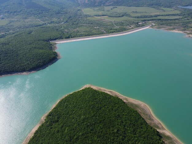 緑の春の森に覆われた山の谷の貯水池の空撮美しい景色