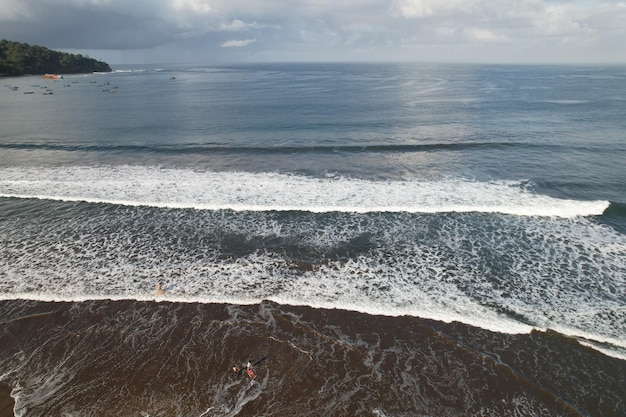 浜辺の波の空撮。波の白い泡が海の波を砕く。