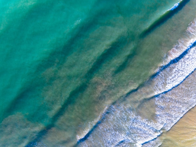 Aerial view of Waves crashing on sandy shoreSea surface ocean waves backgroundTop view beach background