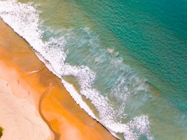 Aerial view of Waves crashing on sandy shoreSea surface ocean waves backgroundTop view beach background