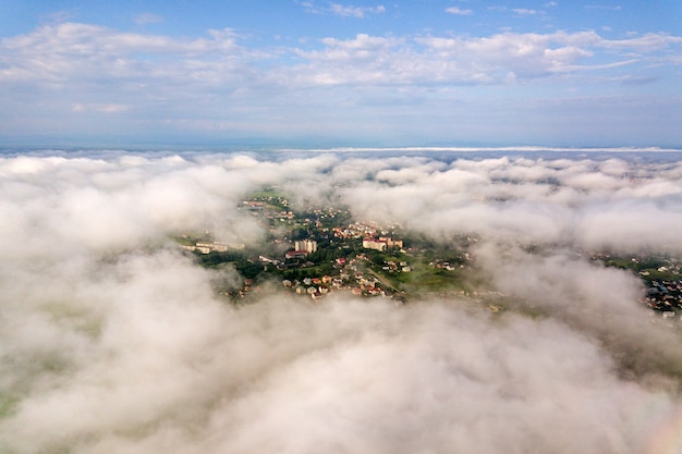 Aerial view of white clouds above a town or village with rows of buildings