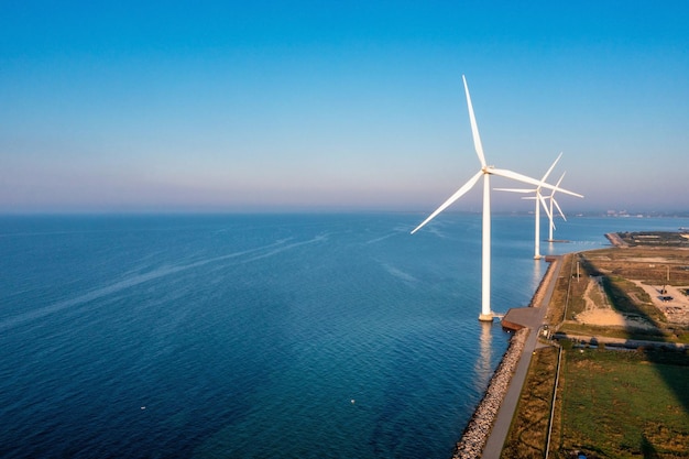 Aerial view of the wind turbines. Green ecological power energy generation. Wind farm eco field. Offshore and onshore windmill farm green energy at sea.