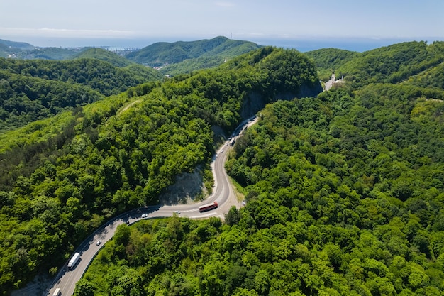 Aerial view of winding road from the high mountain pass great road trip trough the dense woods birds