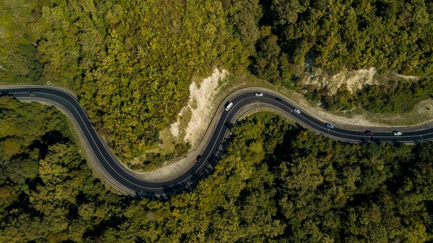 Aerial view of winding road from the high mountain pass Great road trip trough the dense woods