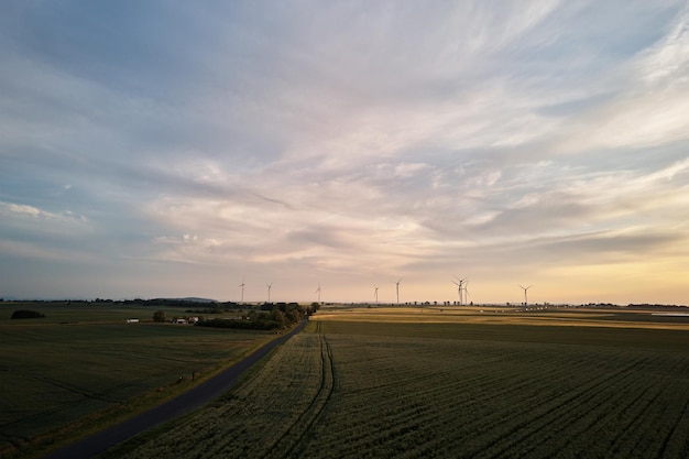 田園地帯のコンセプト o の美しい夕焼け空に対する風車タービン発電機の空撮