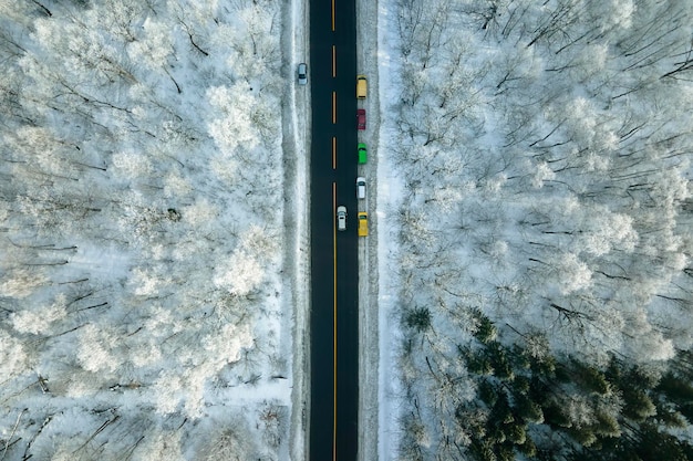 추운 겨울 날에 눈 인 숲과 검은 아스팔트 숲 도로와 함께 겨울 풍경의 공중 풍경