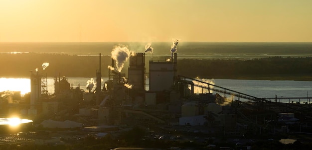 Aerial view of wood processing factory with smoke from production process polluting atmosphere at plant manufacturing yard Industrial site at sunset