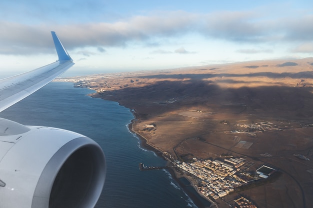 グランカナリア島の航空写真と、窓から飛行機の翼。フライトや休暇の概念。