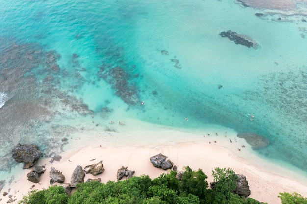 Aerial views of rocky and sandy beach and turquoise ocean at low tide