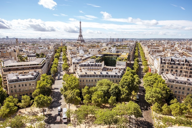 Aerial wide angle cityscape view on the beautiful buildings and avenues with Eiffel tower on the background during the sunny day in Paris