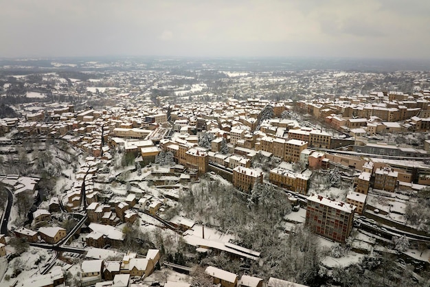 Aerial winter landscape of dense historic center of Thiers town in PuydeDome department AuvergneRhoneAlpes region in France Rooftops of old buildings and narrow streets at snowfall