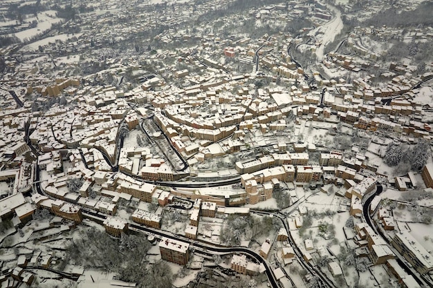 Aerial winter landscape of dense historic center of Thiers town in PuydeDome department AuvergneRhoneAlpes region in France Rooftops of old buildings and narrow streets at snowfall