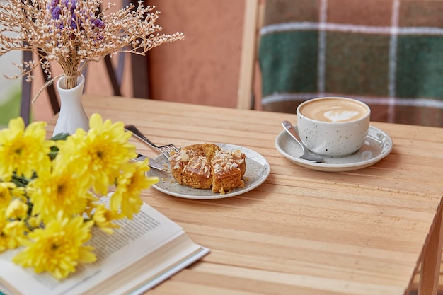 Aesthetic autumn lunch coffee time for yourself book and\
dessert cutting doughnut with cappuccino among chrysanthemum\
atmospheric lunch guilty pleasure