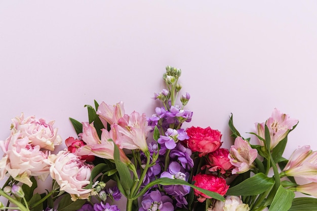 Aesthetic background with colourful red and pink rose flowers on pink background Beautiful floral composition