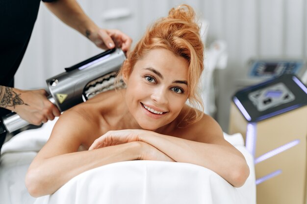 Aesthetic body treatment. Cropped portrait of young slender careful woman having professional massaging procedure at her back