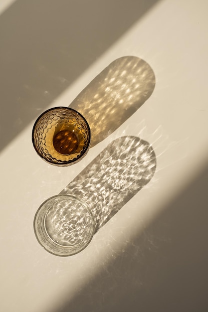 Aesthetic bohemian crystal glass with sparkling sunlight shadow on the neutral beige background Flat lay top view