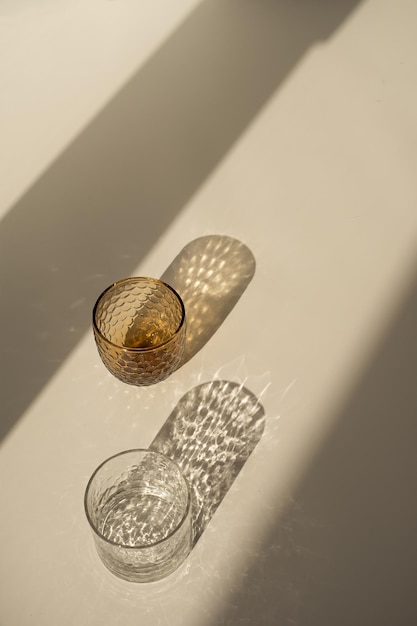 Aesthetic bohemian crystal glass with sparkling sunlight shadow on the neutral beige background