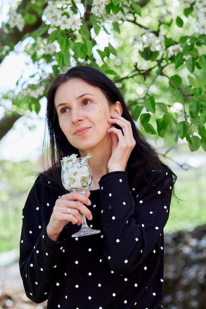 Aesthetic girl holds glass full of flowers practicing spiritual
breathwork meditation outside connecting with nature blooming tree
spring vibes