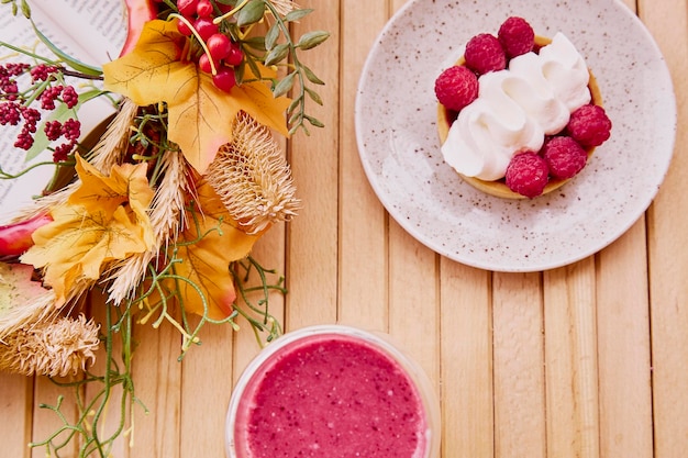 Aesthetic healthy autumn lunch pink strawberry smoothie and french tart on the wooden table