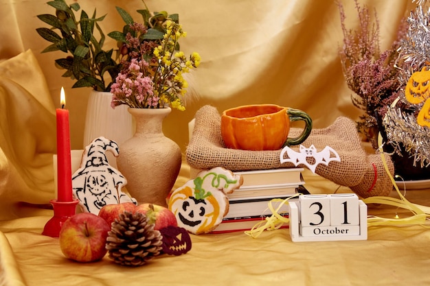 Aesthetic home party with trendy Halloween tree and decorations Autumn holidays Cozy Halloween with candles orange mug dry flowers cookies in shape of pumpkin and ghost with books and calendar