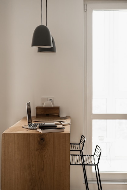 Эстетичный минималистичный дизайн интерьера дома, гостиной. Подвесные светильники, деревянная подставка с портативным компьютером