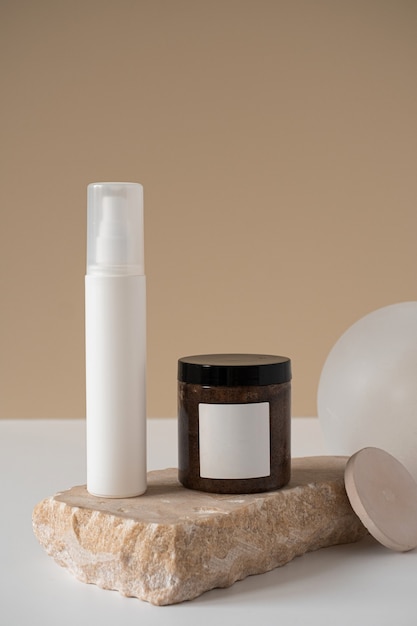 Aesthetic minimalist beauty care therapy concept. Spray bottle, blank body cream jar, marble stone against neutral beige