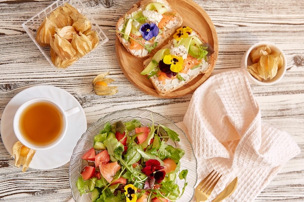 Aesthetic pescetarian table toasts with salmon cottage cheese edible flowers. Mediterranean salad.